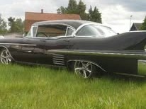 Svart Cadillac 1958 på gräset med kromfälgar