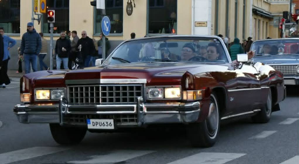 Vinröd Cadillac Eldorado cabriolet i cruisingkö genom stadskärnan