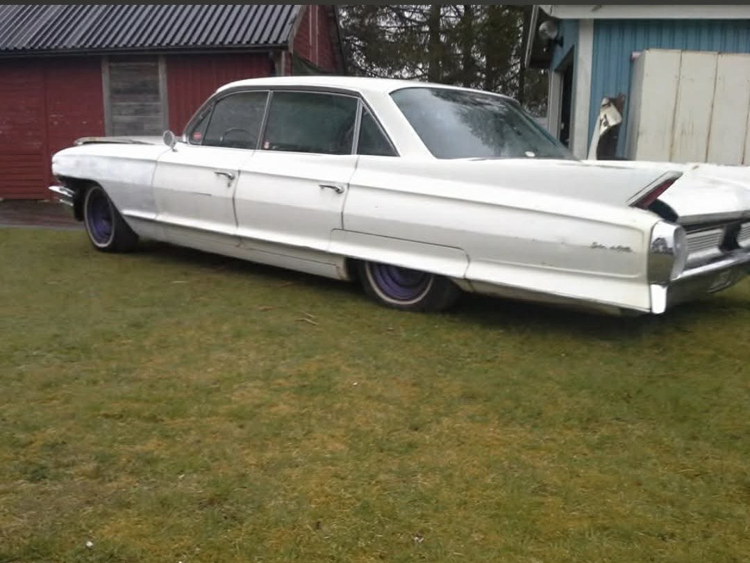 Vit Cadillac fyradörrars i original skick på gräsmattan